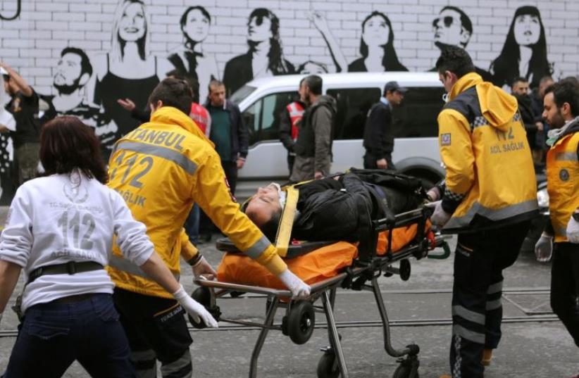 A man is helped by emergency services following a suicide bombing in a major shopping and tourist district in central Istanbul (photo credit: REUTERS)