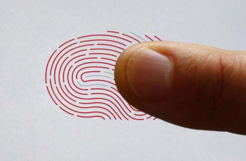 A person uses a sensor for biometric identification on a smartphone in Berlin (photo credit: REUTERS)