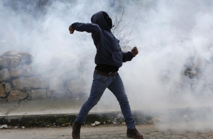 A Palestinian throws stones at Israeli forces in a clash at Arroub refugee camp, February 11. (photo credit: REUTERS)