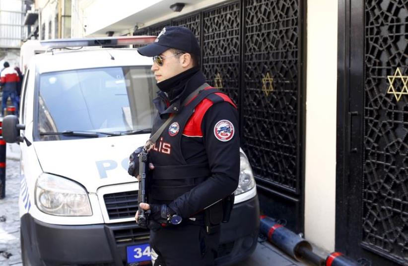 A Turkish police officer stands guard in front of a synagogue in Istanbul (photo credit: REUTERS)
