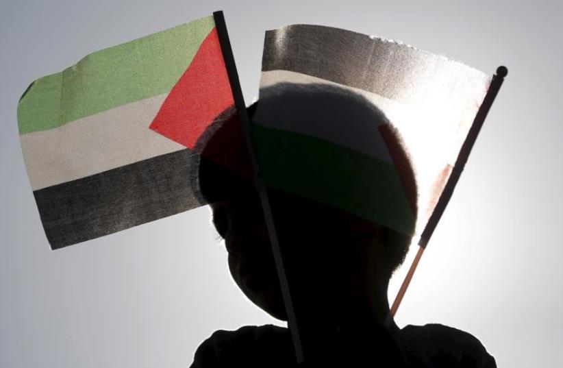 A Beduin boy holds Palestinian flags as he takes part in a rally marking Land Day in Umm el-Hiran (photo credit: REUTERS)
