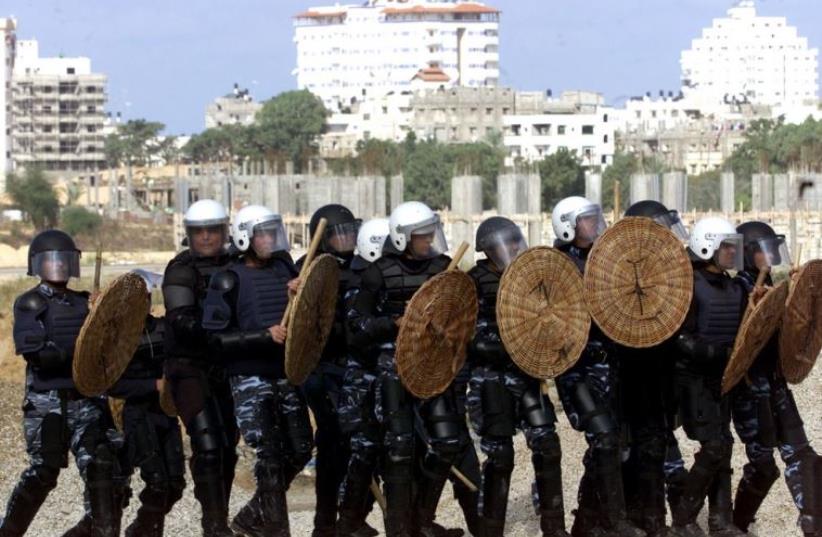 Palestinian policemen clash with stone throwers in Gaza (photo credit: REUTERS)