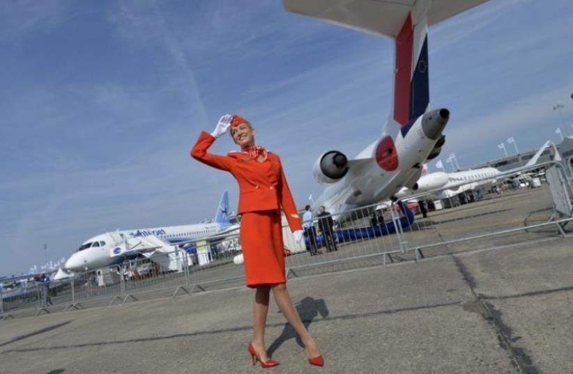 A flight attendant salutes to visitors during the International Paris Airshow at Le Bourget (photo credit: AFP PHOTO)
