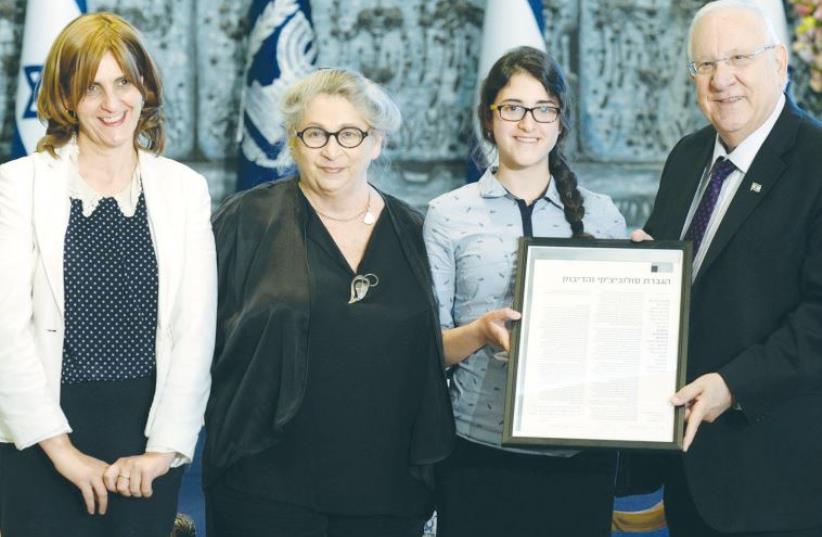 PRESIDENT REUVEN RIVLIN and his wife, Nechama, present a certificate of recognition yesterday to Yisca Shaki, who won first prize in a writing competition for a story she wrote inspired by Shai Agnon, as Shaki’s mother looks on (photo credit: MARK NEYMAN / GPO)