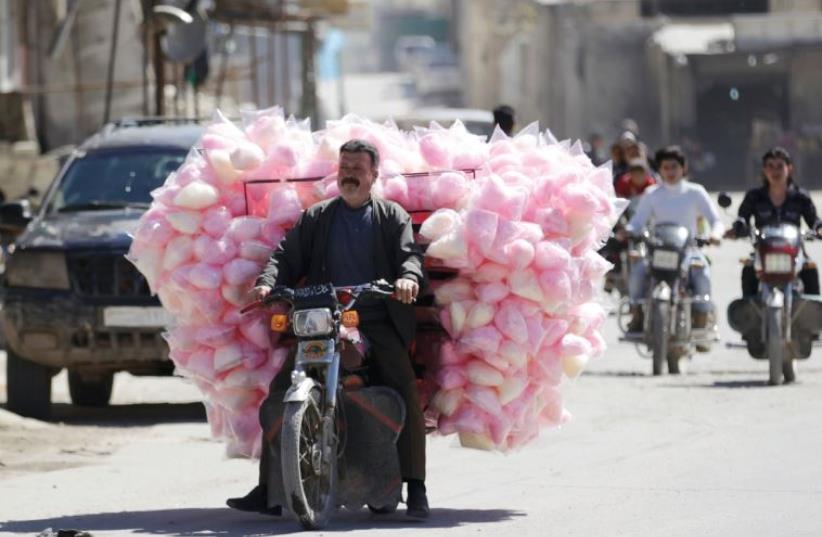 A cotton-candy seller drives along a street in the rebel-controlled area of Maaret al-Numan in Idlib province last week (photo credit: REUTERS)