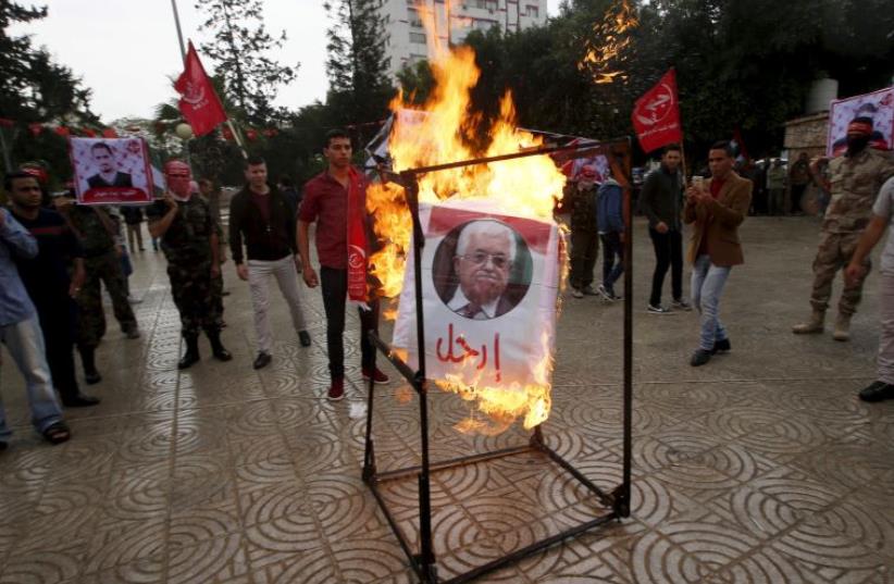 Supporters of the Popular Front for the Liberation of Palestine (PFLP) burn a poster of Palestinian President Mahmoud Abbas during a protest against Abbas's policies, in Gaza City April 12, 2016 (photo credit: REUTERS)