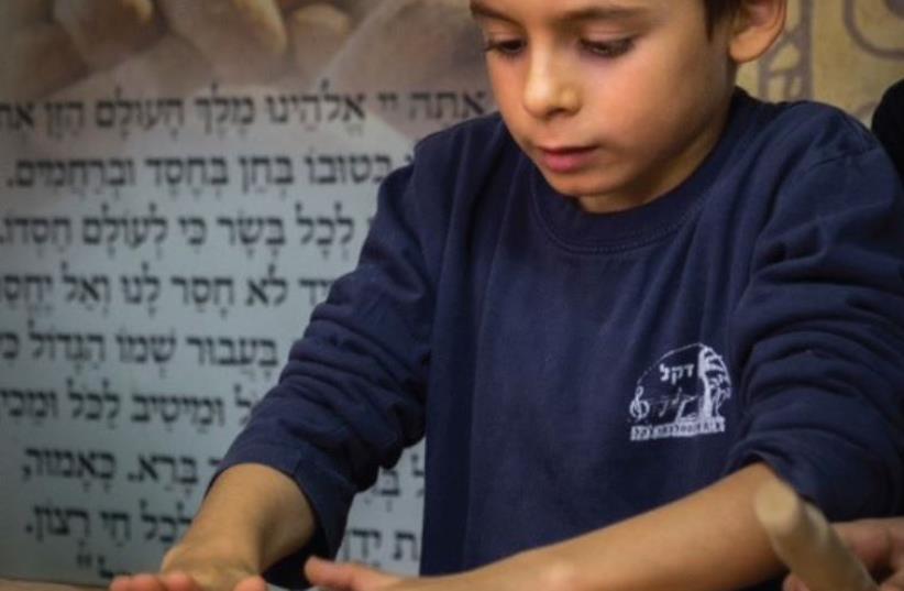 A boy bakes matzot at Chabad’s matza factory in Ra’anana (photo credit: MOSHE KWART)