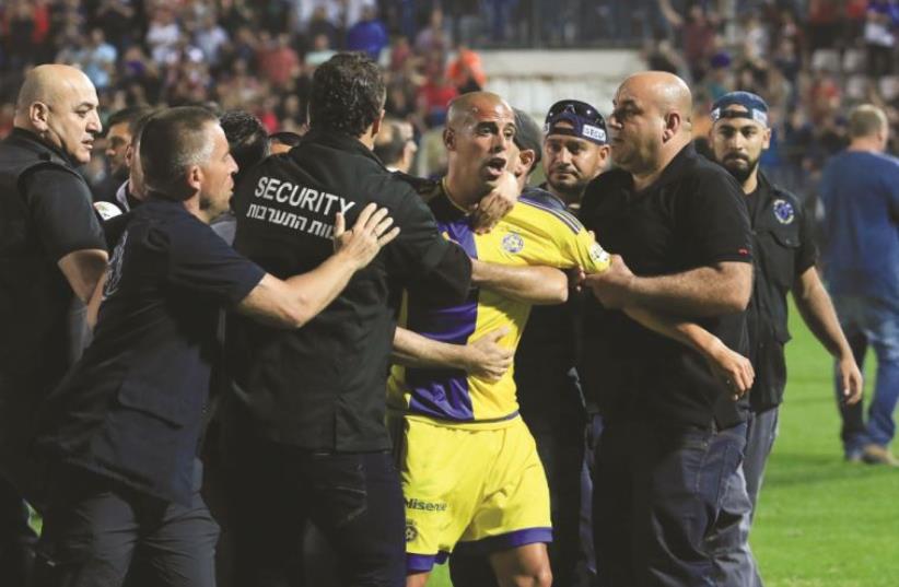 Maccabi Tel Aviv winger Tal Ben-Haim (center) had to be escorted off the pitch after the brawl that followed Monday’s match at Bnei Sakhnin, a brawl during which Maccabi goalkeeper Predrag Rajkovic shoved Sakhnin coach Yossi Abuksis to the ground for which he was suspended for three matches on Wedne (photo credit: ERAN LUF)