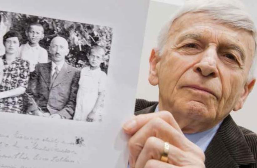 Auschwitz survivor and plaintiff Max Eisen holds a photo of himself and his Hungarian Jewish family before their deportation during the Holocaust (photo credit: AFP PHOTO)