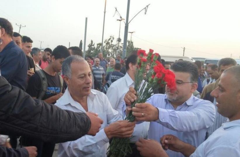 Hadash MKs giving flowers to Palestinians at checkpoint in honor of May Day (photo credit: JOINT LIST)