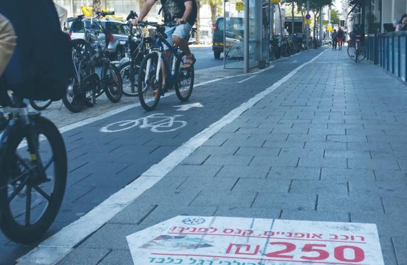 TEL AVIV BICYCLISTS stick to one of the city’s bike lanes yesterday as they pass a printed sidewalk warning that reads: Bicycle rider, there’s a fine ahead! NIS 250. The sidewalk is for pedestrians only (photo credit: BEN HARTMAN)