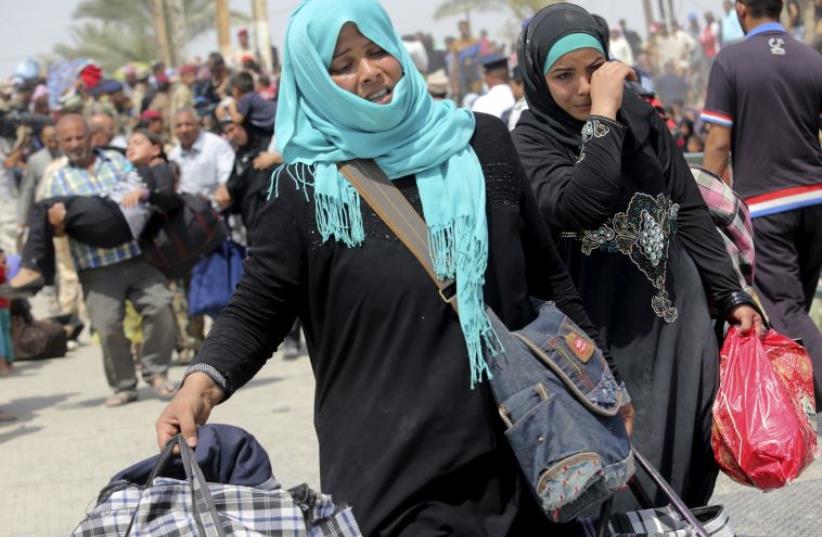 Displaced Sunni women fleeing the violence in Ramadi, carry bags as they walk on the outskirts of Baghdad, May 24, 2015. (photo credit: REUTERS)