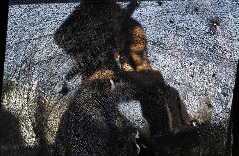 An ultra-Orthodox Jewish man is seen through a damaged car window after a rocket fired from Gaza landed in the southern city of Ashdod, November 16, 2012 (photo credit: REUTERS)