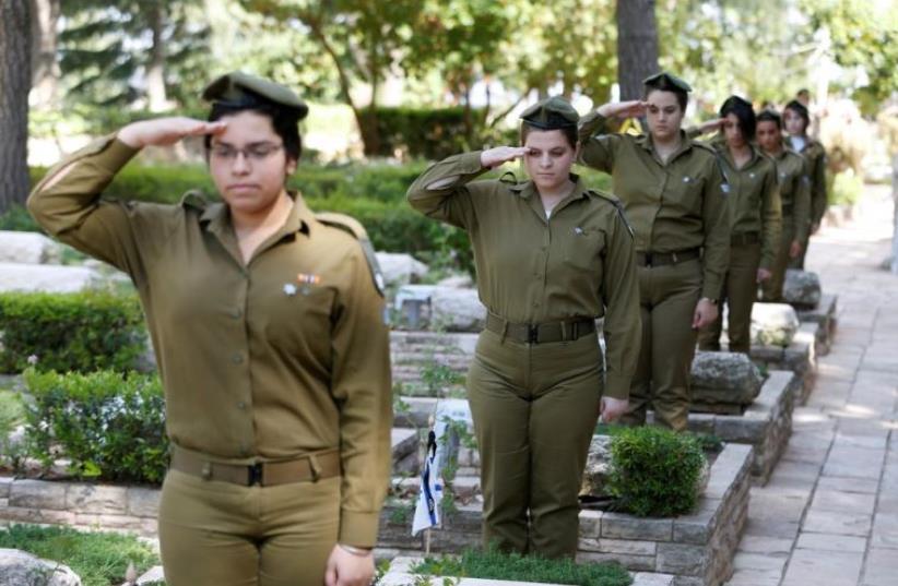 Israeli soldiers salute as they stand next to graves of fallen soldiers at Mt. Herzl military cemetery in Jerusalem (photo credit: REUTERS)