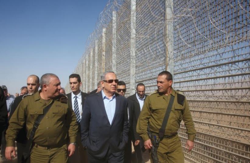 Prime Minister Benjamin Netanyahu (center) walks next to Chief of Staff Lieutenant General Gadi Eizenkot (left) during a visit to the border fence between Israel and Jordan near Eilat in February (photo credit: MARC ISRAEL SELLEM)