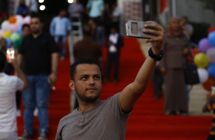 A Palestinian man takes a selfie during the opening ceremony of the Red Carpet festival in Gaza City, on 12 May 2016. (photo credit: MOHAMMED ABED / AFP)