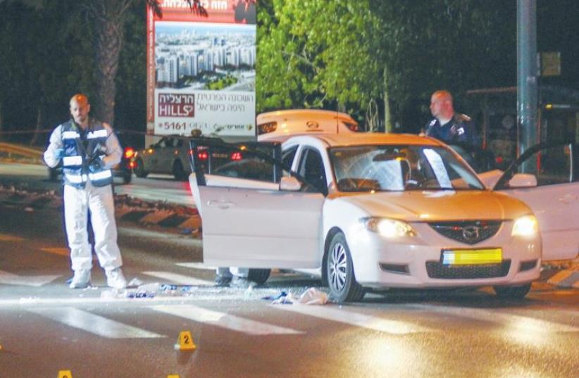 A FORENSICS OFFICER examines the car in Tel Aviv in which mob prince Shay Shirazi was shot to death by a rival mob’s hit man last week. (photo credit: FLASH90)