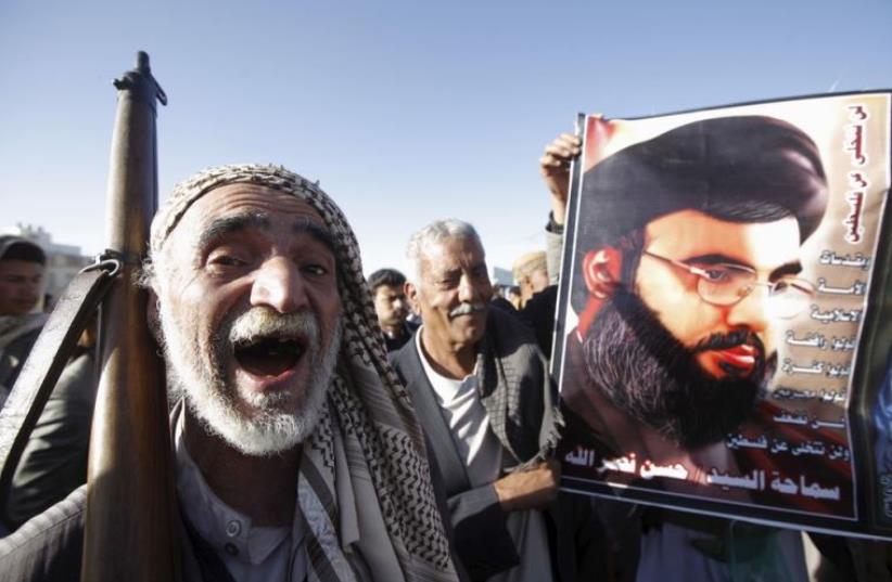 A Houthi militant shouts slogans as he stands next a poster of Hezbollah leader Hassan Nasrallah during a rally against US support to Saudi-led air strikes in Sanaa (photo credit: REUTERS)