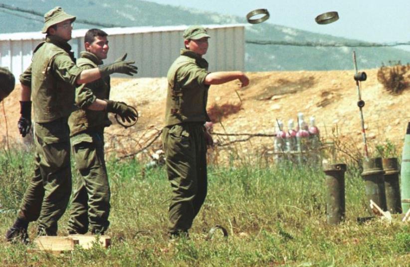 IDF soldiers on base along the Lebanese border play hoops in April 1996 as they try to toss metal rings from artillery shells onto shells stacked up and ready to be fired into Lebanon (photo credit: REUTERS)