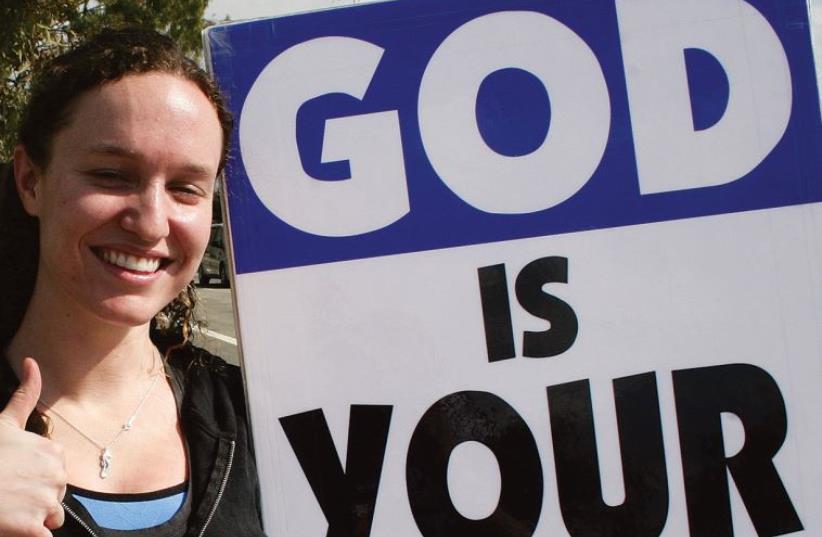 Megan Phelps-Roper holding a "God is your enemy" sign (photo credit: DAVID ABITBOL)