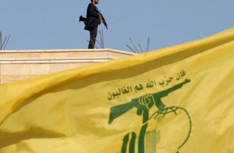 A Hezbollah member carries his weapon on top of a building in Bekaa Valley (photo credit: REUTERS)