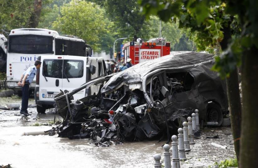 A destroyed van is pictured near a Turkish police bus which was targeted in a bomb attack in a central Istanbul district, Turkey, June 7, 2016.  (photo credit: REUTERS)
