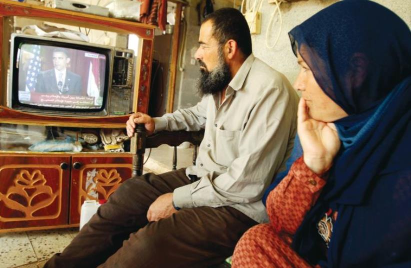Gazan Palestinians watch a television broadcasting the speech of US President Barack Obama in Cairo, in June 2009 (photo credit: REUTERS)
