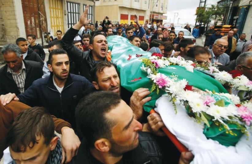 Mourners carry the body of Palestinian assailant Abdel Fattah al-Sharif, who was shot and killed after being wounded last March by an Israeli soldier, during his funeral in Hebron on May 28 (photo credit: REUTERS)