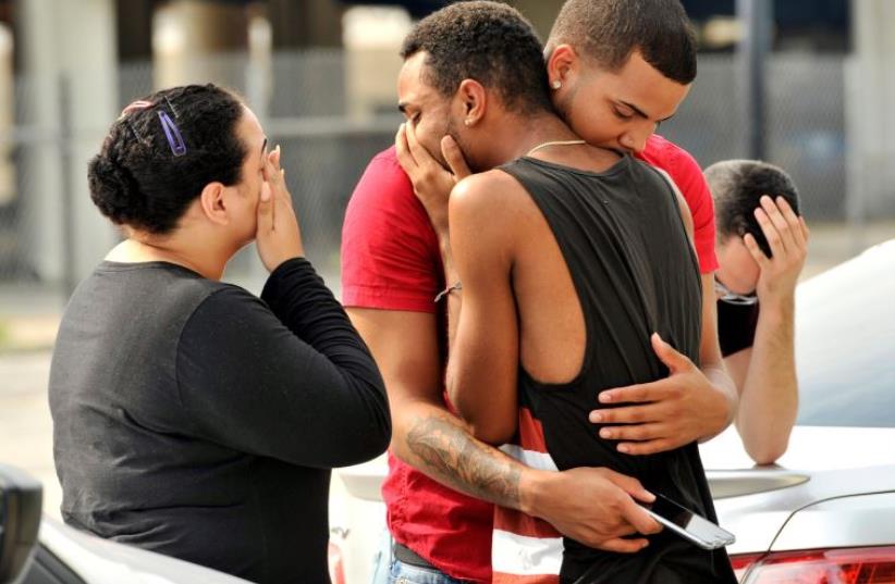 Friends and family members embrace outside the Orlando Police Headquarters during the investigation of a shooting at the Pulse night club, where as many as 20 people have been injured after a gunman opened fire, in Orlando, Florida, US June 12, 2016. (photo credit: STEVE NESIUS/REUTERS)