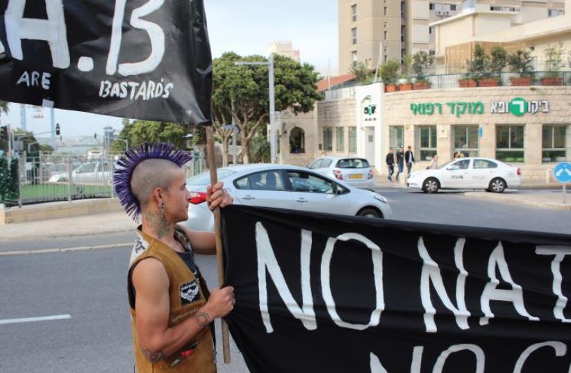 A man carries a sign reading 'No nation, no borders, no gods, no masters' during a rally to mark 'May Day,' in Haifa, May 1 (photo credit: HUNTER STUART)