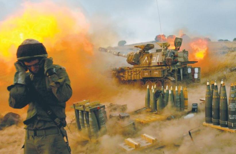 AN ISRAELI soldier stands near a mobile artillery unit as it fires a shell into southern Lebanon on July 13, 2006, a day after IDF reservists Ehud Goldwasser and Eldad Regev were abducted by Hezbollah (photo credit: REUTERS)