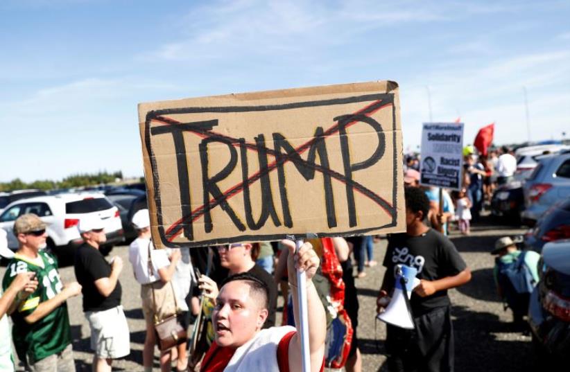 A demonstrator holds a sign against Republican U.S. presidential candidate Donald Trump outside his campaign rally in Sacramento, California (photo credit: REUTERS)