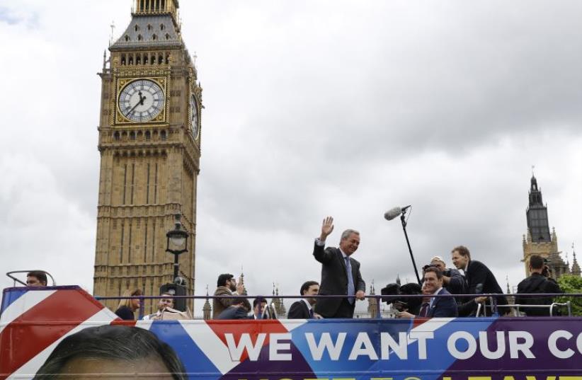 Leader of the United Kingdom Independence Party (UKIP) Nigel Farage waves a launch for an EU referendum poster from a bus at Parliament Square in London, Britain June 16, 2016. (photo credit: REUTERS)