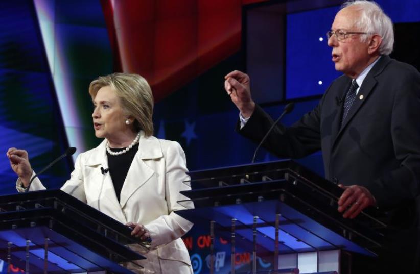 DATE IMPORTED: April 15, 2016 Democratic U.S. presidential candidate Hillary Clinton (L) listens to Senator Bernie Sanders speak during a Democratic debate hosted by CNN and New York One at the Brooklyn Navy Yard in New York April 14, 2016.  (photo credit: REUTERS)