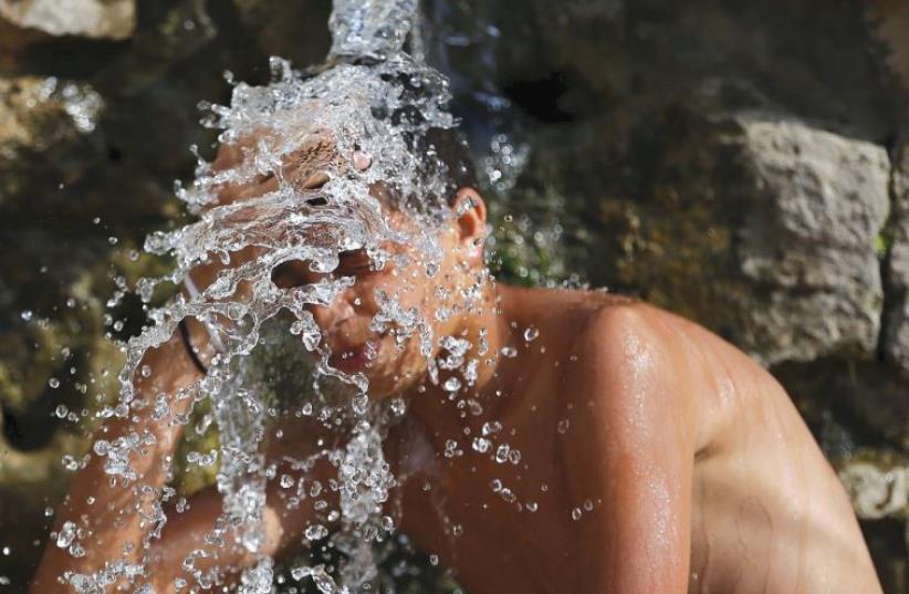 PALESTINIAN YOUTH takes a shower at a natural spring near Beit Jala, south of Jerusalem, on a hot day last summer (photo credit: REUTERS/AMMAR AWAD)