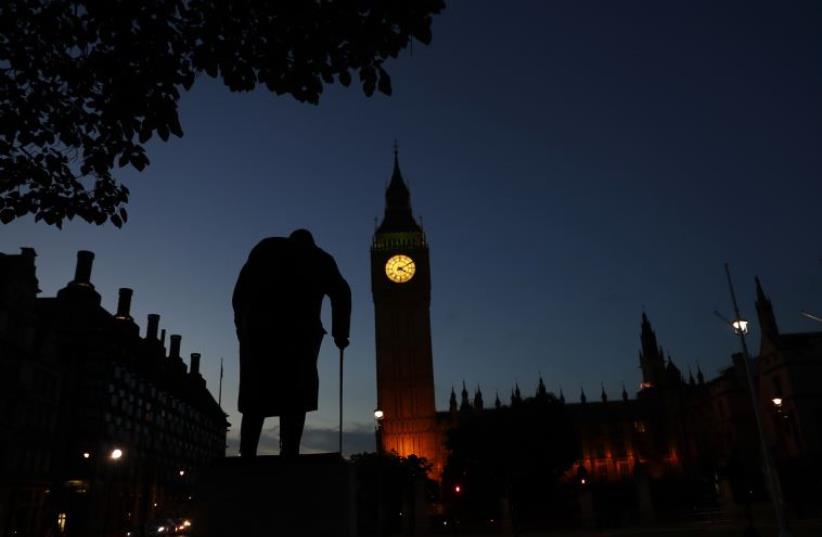Dawn breaks behind the Houses of Parliament and the statue of Winston Churchill in Westminster, London, Britain June 24, 2016 (photo credit: STEFAN WERMUTH/REUTERS)