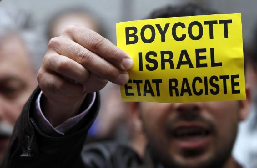 A demonstrator displays a sign reading "Boycott Israel, racist state" (photo credit: REUTERS)