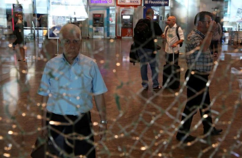 A man looks at a broken glass at Istanbul Ataturk airport, Turkey, following yesterday's blast June 29, 2016. (photo credit: REUTERS)