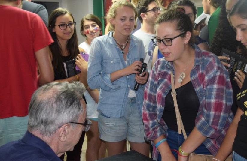 Moshe Arens signs copies of his book 'Flags over the Warsaw Ghetto' for students from Boston Onward Israel Monday night in Jerusalem. (photo credit: Courtesy)