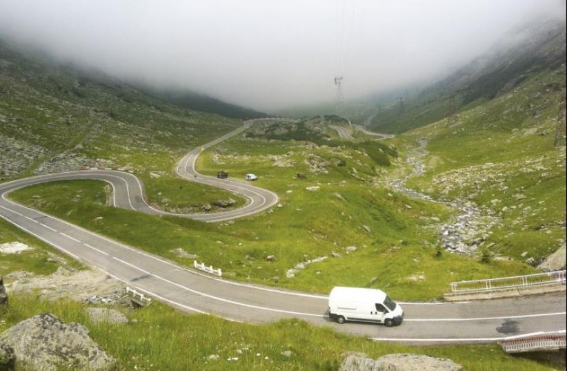 A van drives along the snaking road ascending the Fagaras Mountains (photo credit: LAURA KELLY)