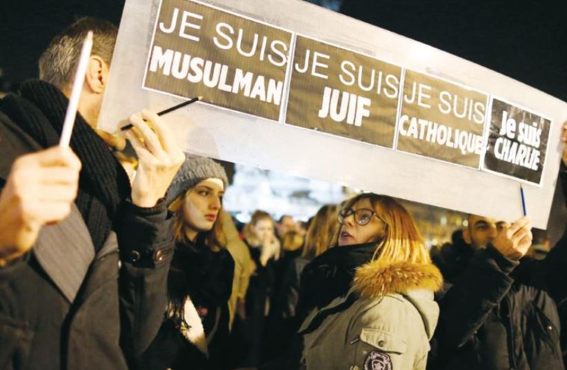 People hold a placard at a vigil in Paris which reads ‘I am Muslim, I am Jewish, I am Catholic, I am Charlie’ following the shooting of 12 people at the satirical magazine ‘Charlie Hebdo’ in January 2015 (photo credit: REUTERS)