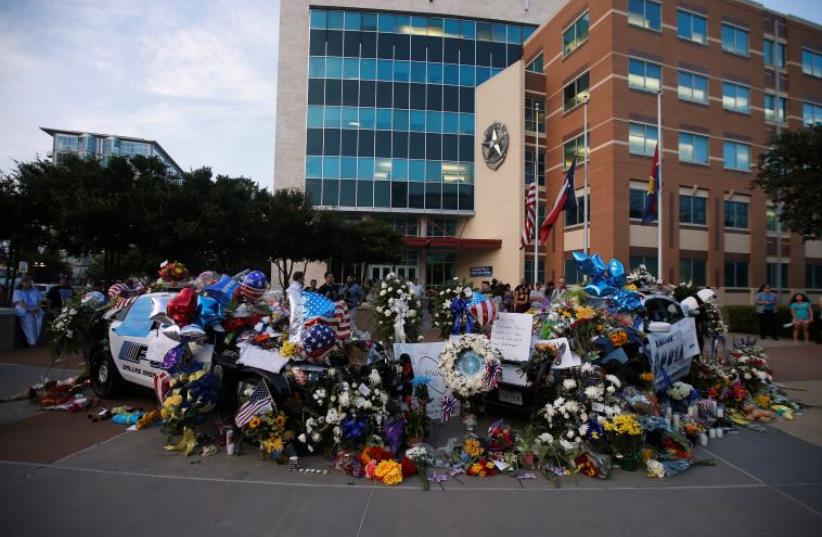 People attend a makeshift memorial at Dallas Police Headquarters following the multiple police shooting in Dallas, Texas, U.S.,July 8, 2016. (photo credit: REUTERS)