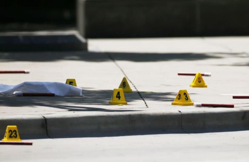 Markers litter the sidewalk as FBI investigators look over a crime scene. (photo credit: REUTERS)