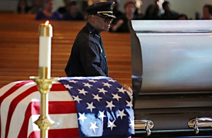 Dallas police Chief David Brown places his hand on a casket for slain Dallas police Sgt. Michael Smith during a visitation for his body Tuesday, July 12, 2016 at Mary Immaculate Catholic Church in Farmers Branch, Texas.  (photo credit: REUTERS)