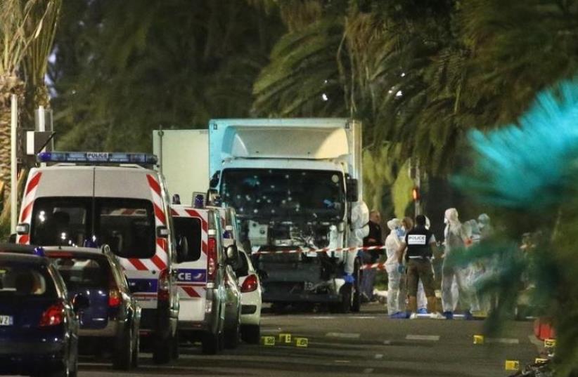 French police forces and forensic officers stand next to a truck July 15, 2016 that ran into a crowd celebrating the Bastille Day national holiday on the Promenade des Anglais killing at least 60 people in Nice, France, July 14.  (photo credit: REUTERS/ERIC GAILLARD)