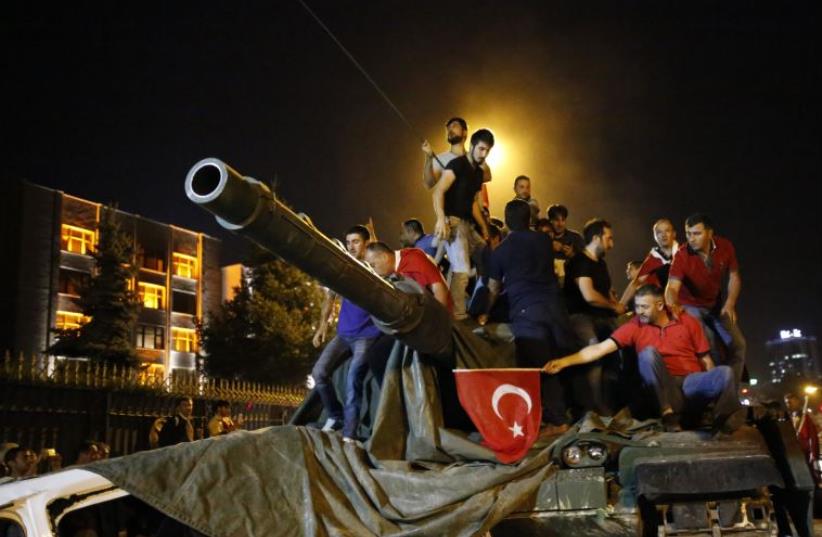 People stand on a Turkish army tank in Ankara, Turkey July 16, 2016 (photo credit: REUTERS)