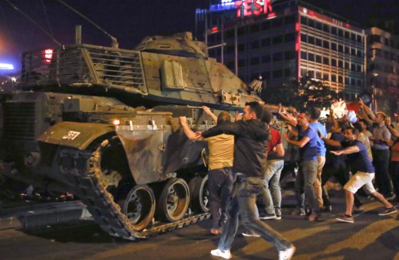 People react near a military vehicle during an attempted coup in Ankara, Turkey, July 16, 2016. (photo credit: REUTERS)