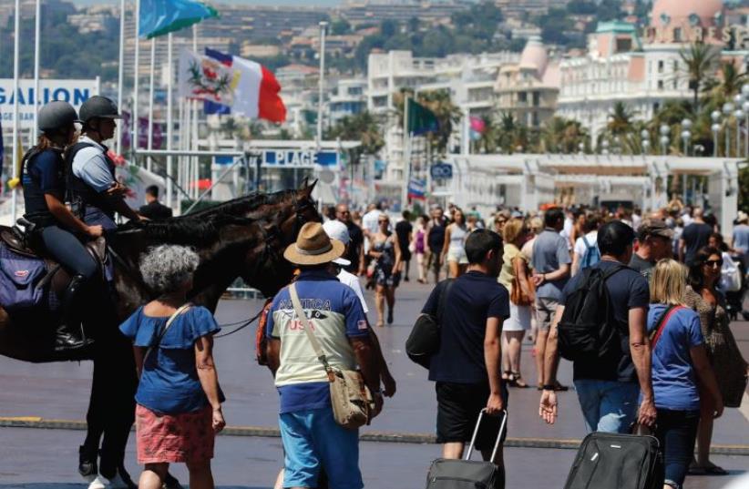 MOUNTED POLICE patrol Nice’s Promenade des Anglais yesterday as tourists with suitcases walk near the site of the Bastille Day terrorist attack. (photo credit: REUTERS)