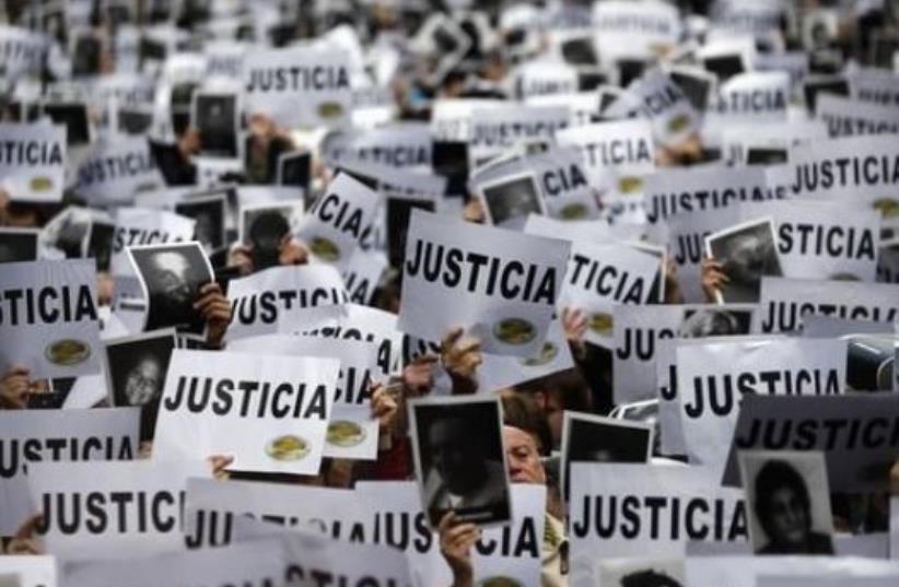 DATE IMPORTED: July 18, 2013 Thousands of people hold up signs reading, "Justice" as they gather to commemorate the 19th anniversary of the 1994 bombing of the Argentine Israeli Mutual Association (AMIA) Jewish community center in Buenos Aires July 18, 2013. (photo credit: REUTERS/MARCOS BRINDICCI)