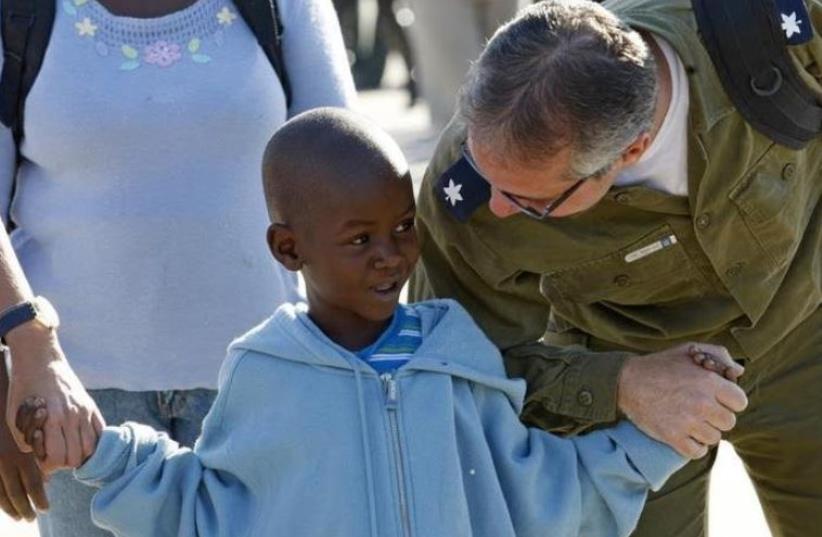 Dr. Yuval Levy, a member of an Israeli military medical team that treated earthquake victims in Haiti, holds hands with Woodley Elize, a six-year-old Haitian boy who would undergo heart surgery in Israel, January 28, 2010 (photo credit: REUTERS)